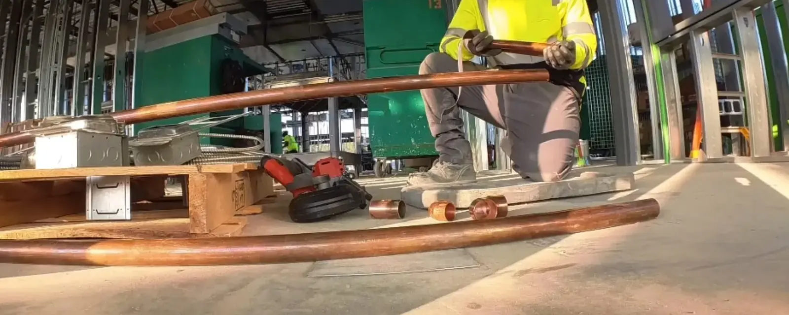 Worker measuring copper pipe at a building site