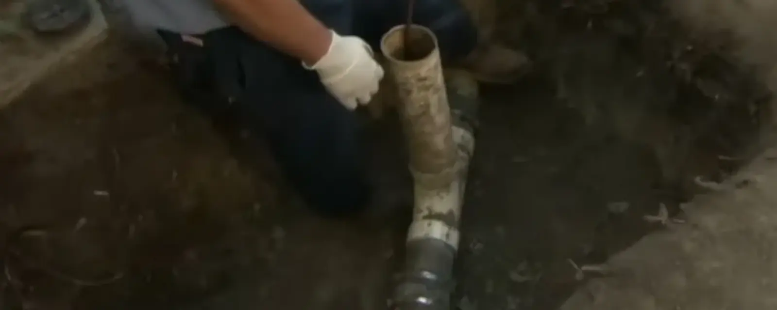 Plumber working on a sewer pipe in an excavated pit