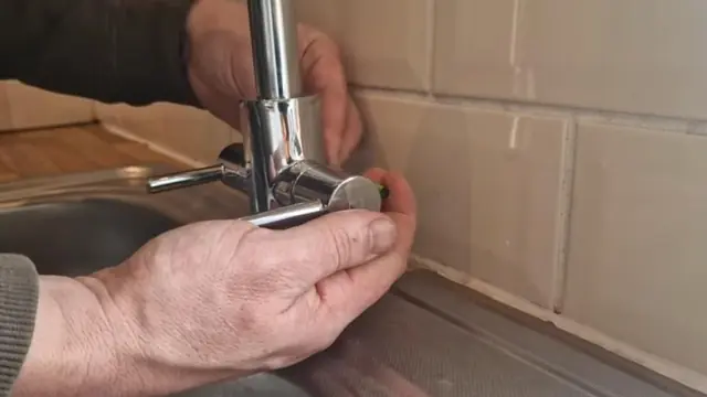 Hands repairing a chrome kitchen faucet
