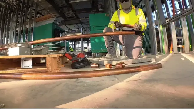 Worker measuring copper pipe at a building site