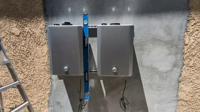 Two wall mounted tankless water heaters on an exterior wall